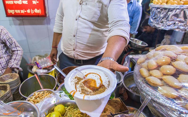 ظرف بهالا در دست آشپزی در میان غذاهای خیابانی آگرا